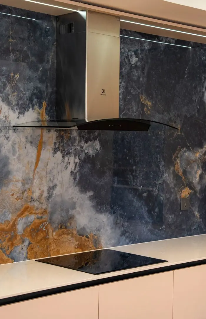 Elegant kitchen featuring a marble backsplash and sleek stainless steel range hood.